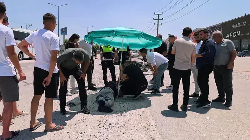 Yerdeki yaralı sürücüyü, ambulans gelene kadar plaj şemsiyesiyle güneşten korudular
