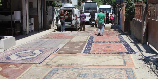 Asfaltlanmayan sokağın tozundan rahatsız olan mahalleli yola halı serdi