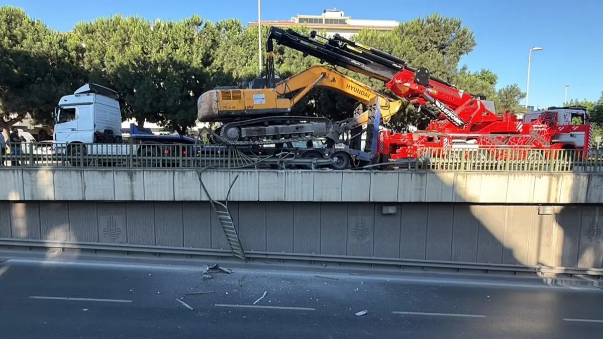 Bahçelievler'de faciadan dönüldü... Tırdan devrilen iş makinesi korkulukta asılı kaldı